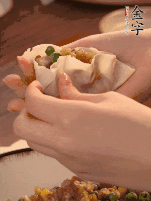 取一大勺餡料放進(jìn)餃子皮里，用大拇指按住頂部餡料，再用虎口掐出形狀。